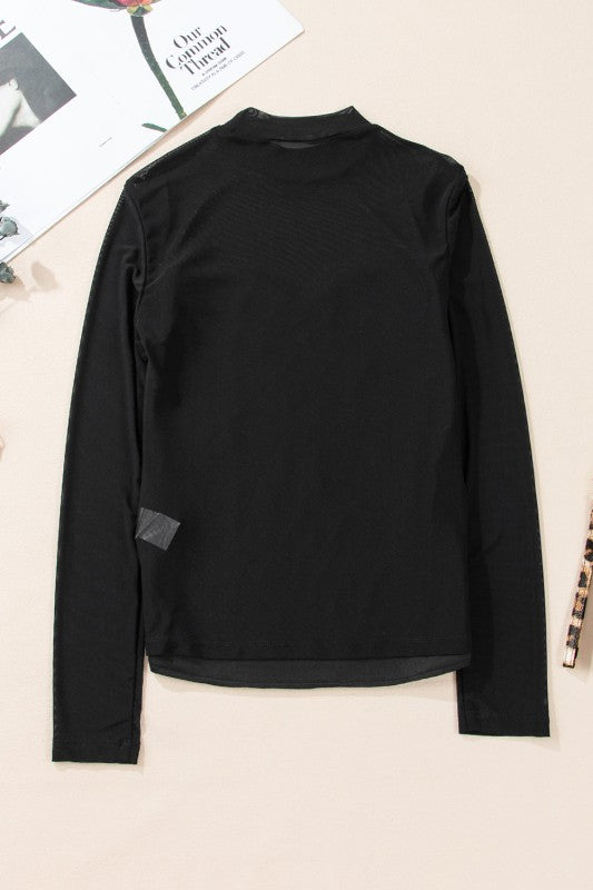 Flat lay of mock neck sequin mesh blouse on white background.