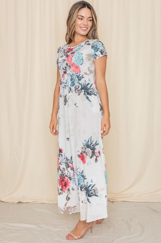 A woman posing in a short sleeve floral maxi gown.