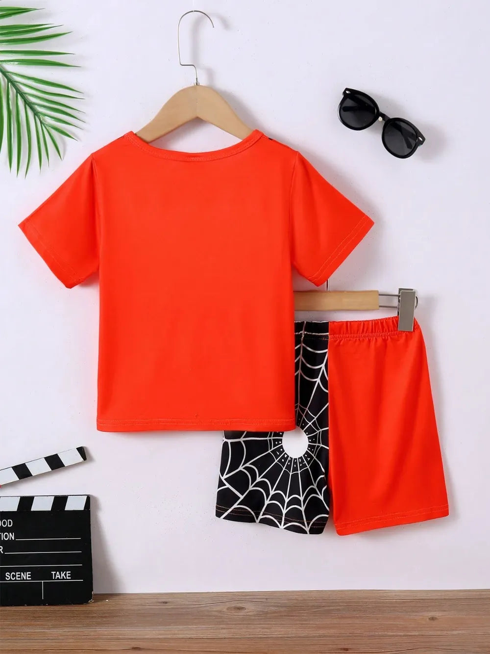 Orange t-shirt and shorts with black spider web design on a white background