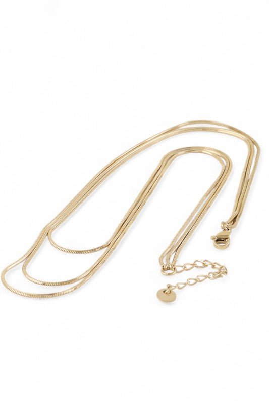 Layered gold necklace set displayed on black velvet, featuring three minimalist chains of varying lengths, perfect for a sleek, modern look.
