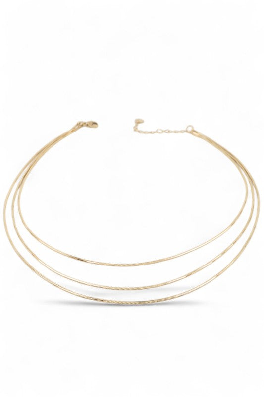 Layered gold necklace set displayed on black velvet, featuring three minimalist chains of varying lengths, perfect for a sleek, modern look.
