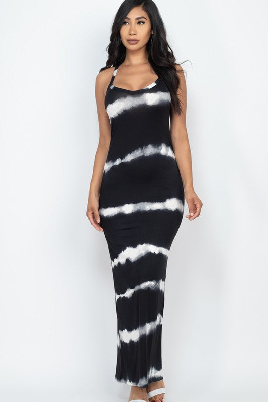 Woman wearing a sleeveless black and white tie-dye maxi dress with spaghetti straps, paired with white sneakers.