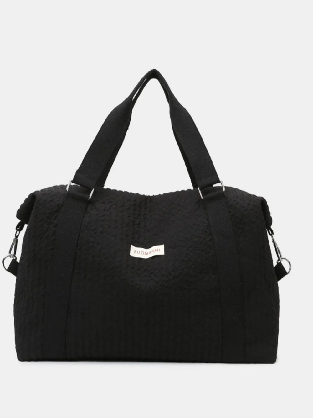 Black textured duffel bag with top handles and a detachable shoulder strap, featuring a small white label.  Set against a plain white background—sleek and minimal design.