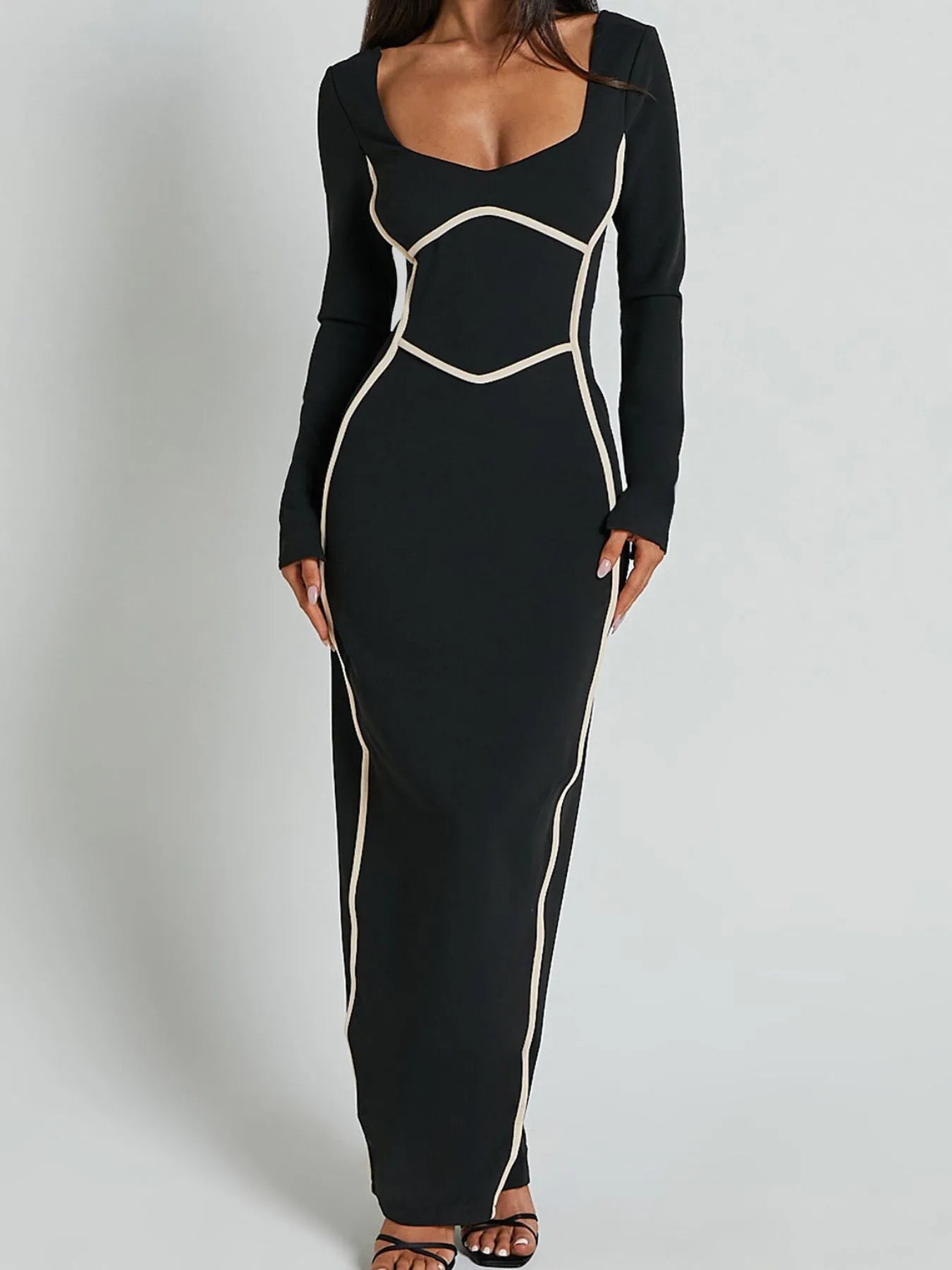 A full length form black dress with long sleeves and white trim details and has a geometric white pattern around the waist and shoulders.