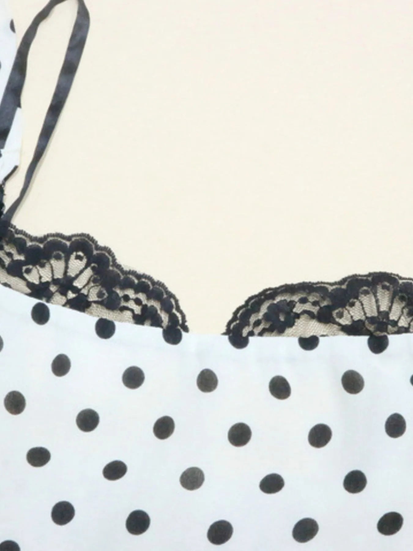 A white, polka-dotted, sleeveless maxi with a fitted bodice and a flared, ruffled hem that reaches the ankles