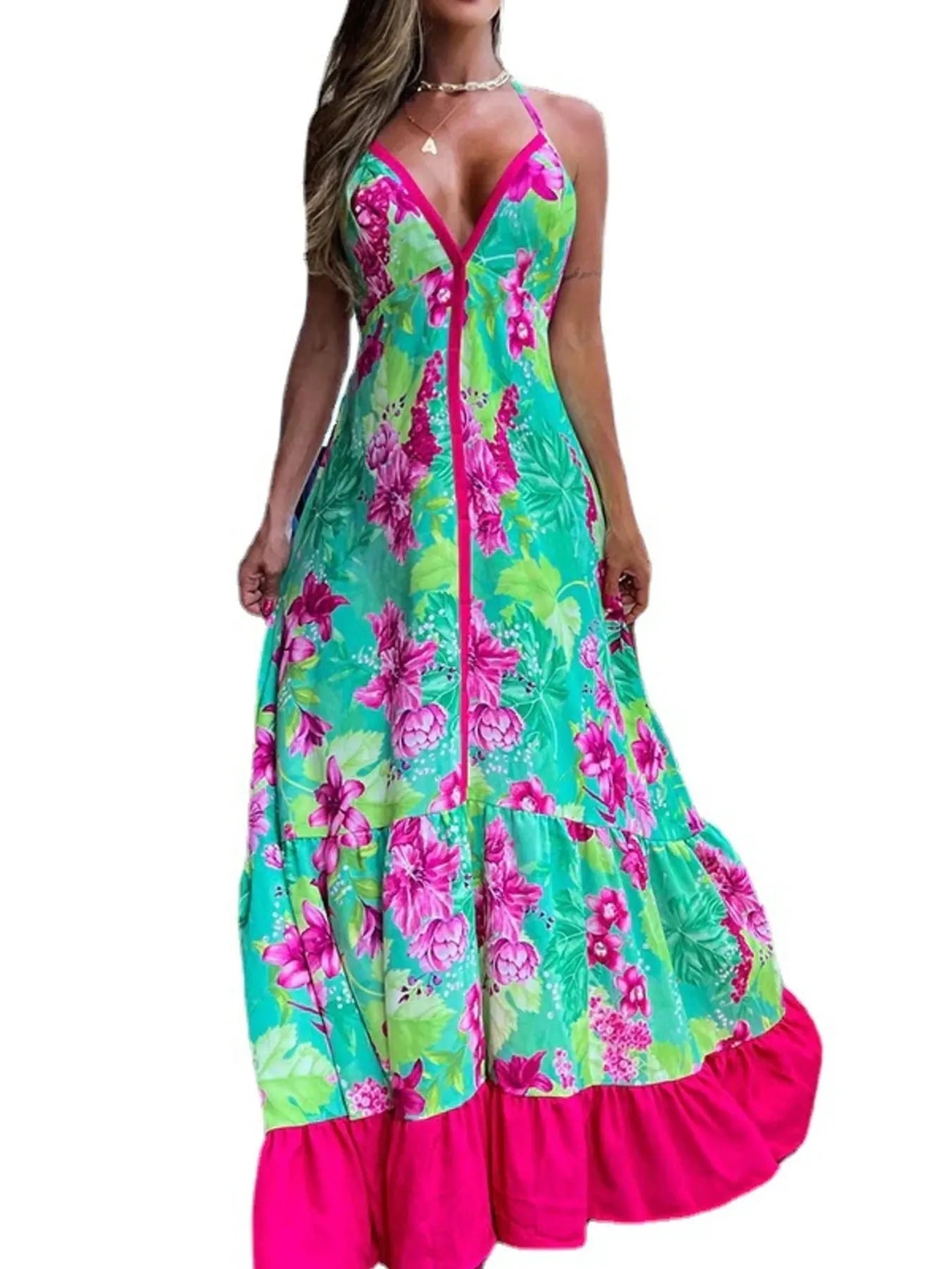 Woman wearing a floral halter-neck maxi dress with deep V-neckline and solid trim, standing by a tropical infinity pool