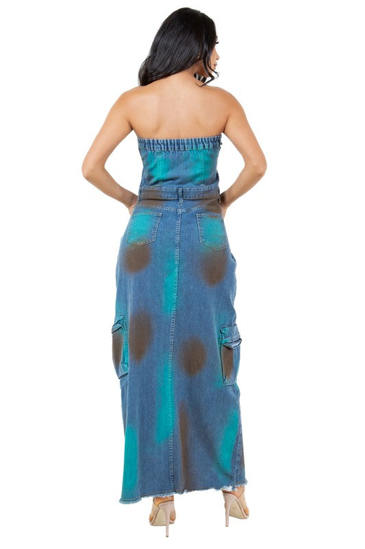 Women’s strapless denim maxi dress with button-front closure, front slit, and oversized utility pockets. Features a distressed tie-dye design in teal and brown tones, styled with clear high-heeled sandals