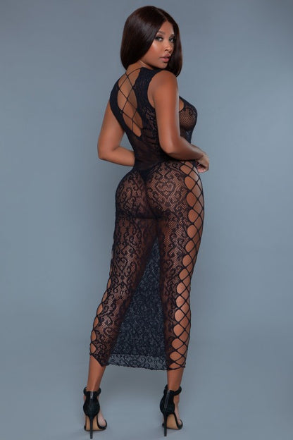 he dress is a sheer, full-length black lace outfit that hugs the body and reveals the undergarments beneath, with long sleeves and a graceful silhouette.