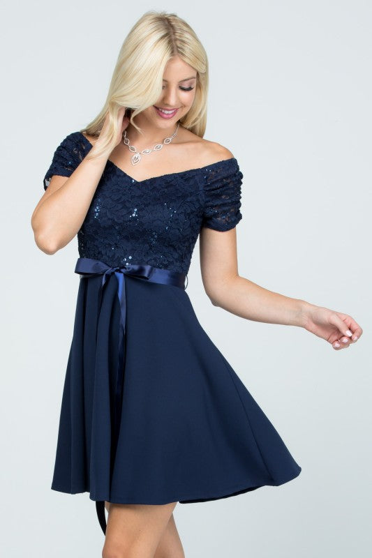 The dress is a navy blue, off-the-shoulder fit-and-flare style with a lace bodice and a satin ribbon belt at the waist.