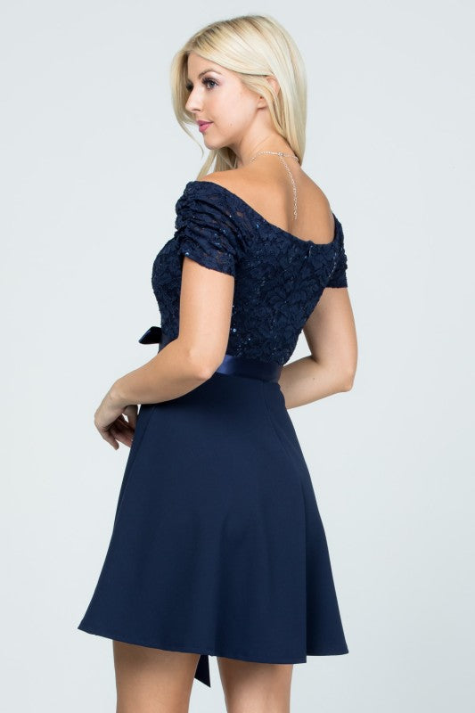 The dress is a navy blue, off-the-shoulder fit-and-flare style with a lace bodice and a satin ribbon belt at the waist.