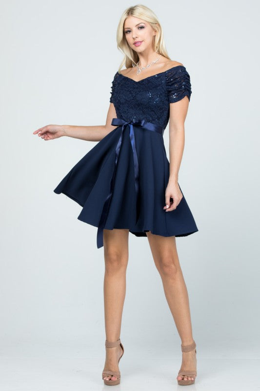 The dress is a navy blue, off-the-shoulder fit-and-flare style with a lace bodice and a satin ribbon belt at the waist.