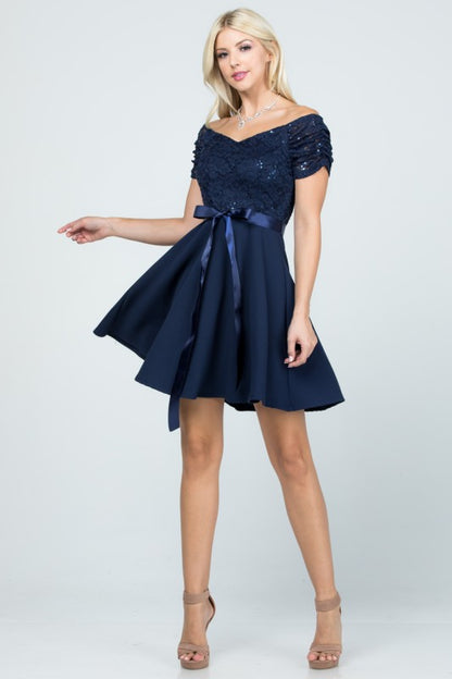 The dress is a navy blue, off-the-shoulder fit-and-flare style with a lace bodice and a satin ribbon belt at the waist.
