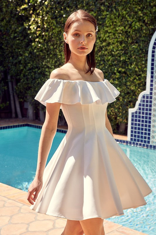 The dress is a short, off-the-shoulder white frock with a dramatic ruffled neckline and a flared, A-line skirt.