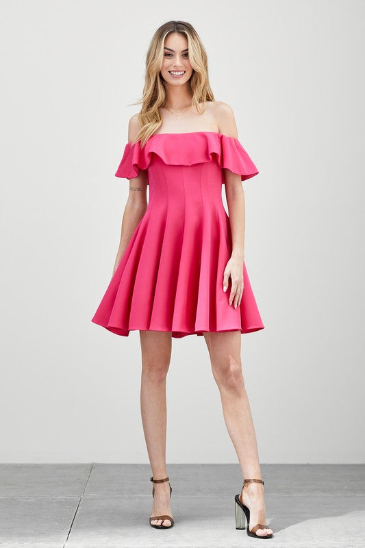 The dress is a short, off-the-shoulder pink frock with a dramatic ruffled neckline and a flared, A-line skirt.