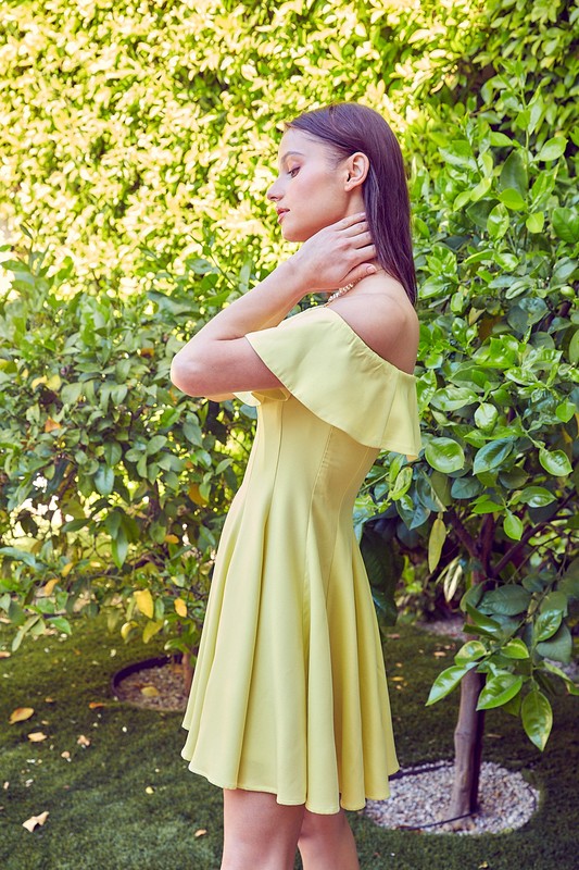 the dress is a short, off-the-shoulder light green frock with a dramatic ruffled neckline and a flared, A-line skirt