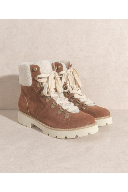 Brown suede hiking boots with white sherpa lining, lace-up front, gold eyelets, and chunky white lug sole.
