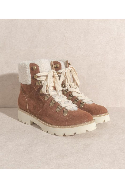 Brown suede hiking boots with white sherpa lining, lace-up front, gold eyelets, and chunky white lug sole.