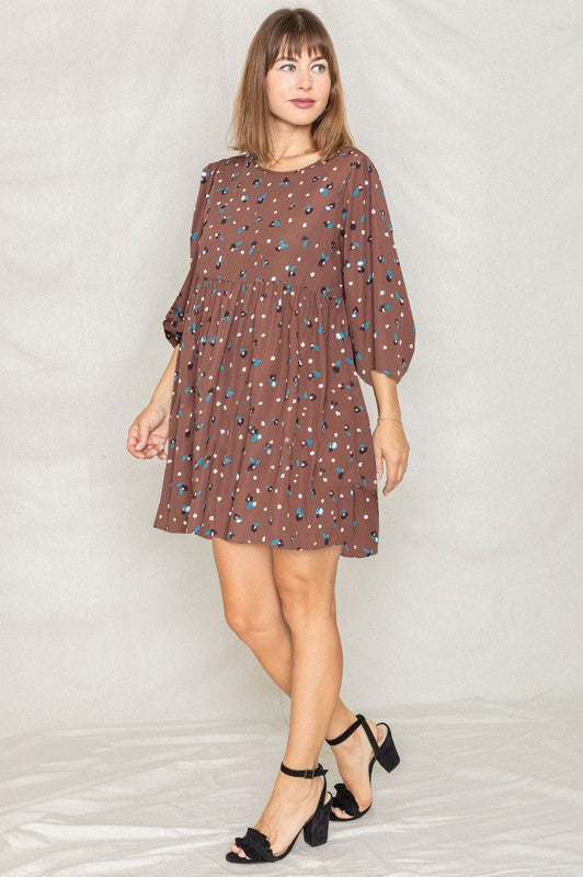 The dress is a short, loose-fitting black shift adorned with a delicate, colorful floral print and three-quarter sleeves