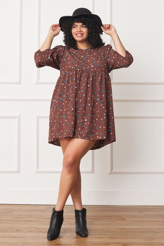 The dress is a short, loose-fitting black shift adorned with a delicate, colorful floral print and three-quarter sleeves
