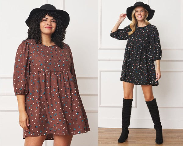The dress is a short, loose-fitting black shift adorned with a delicate, colorful floral print and three-quarter sleeves