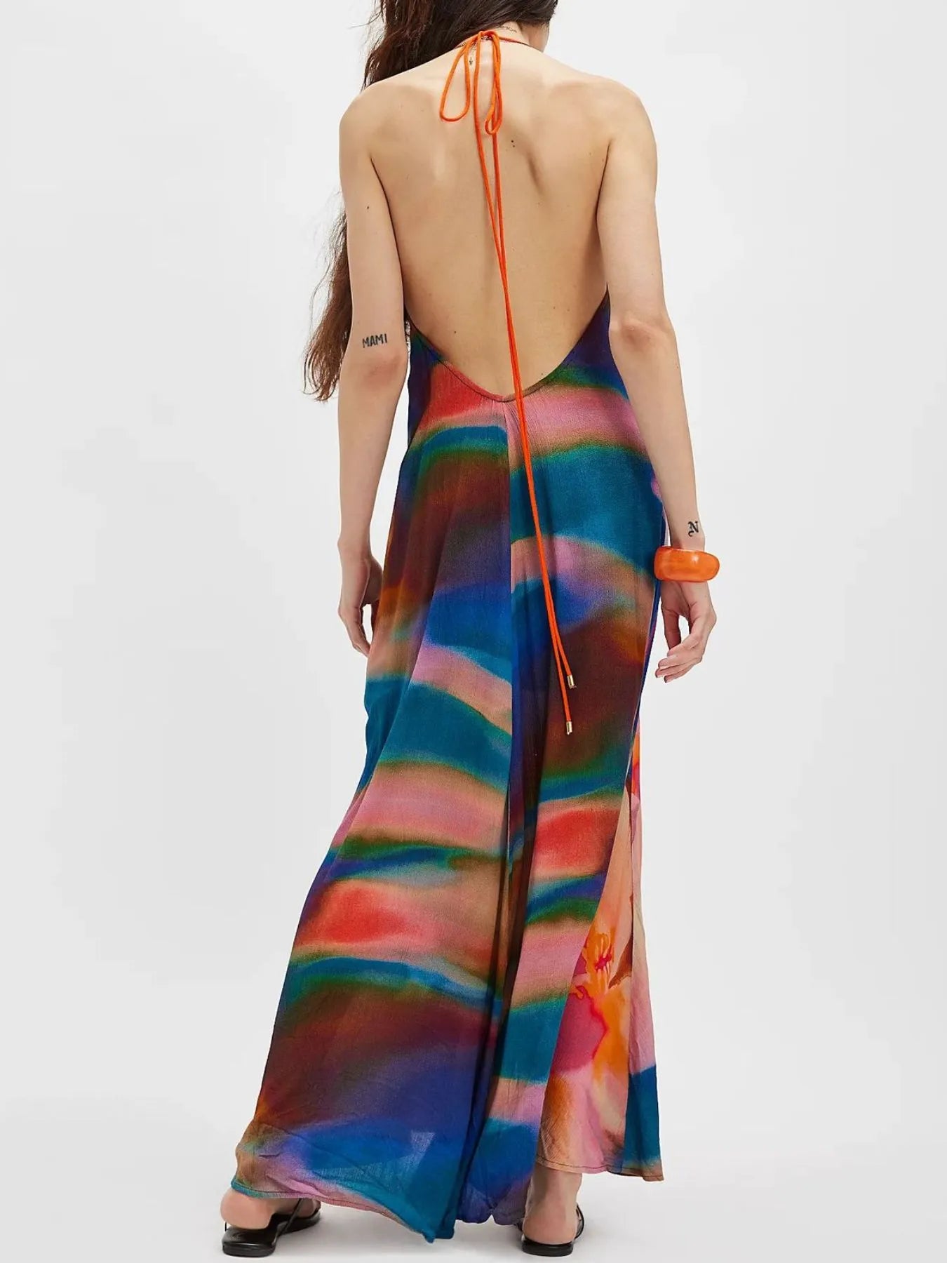Woman wearing a flowing abstract print halter-neck maxi cami dress with deep neckline.