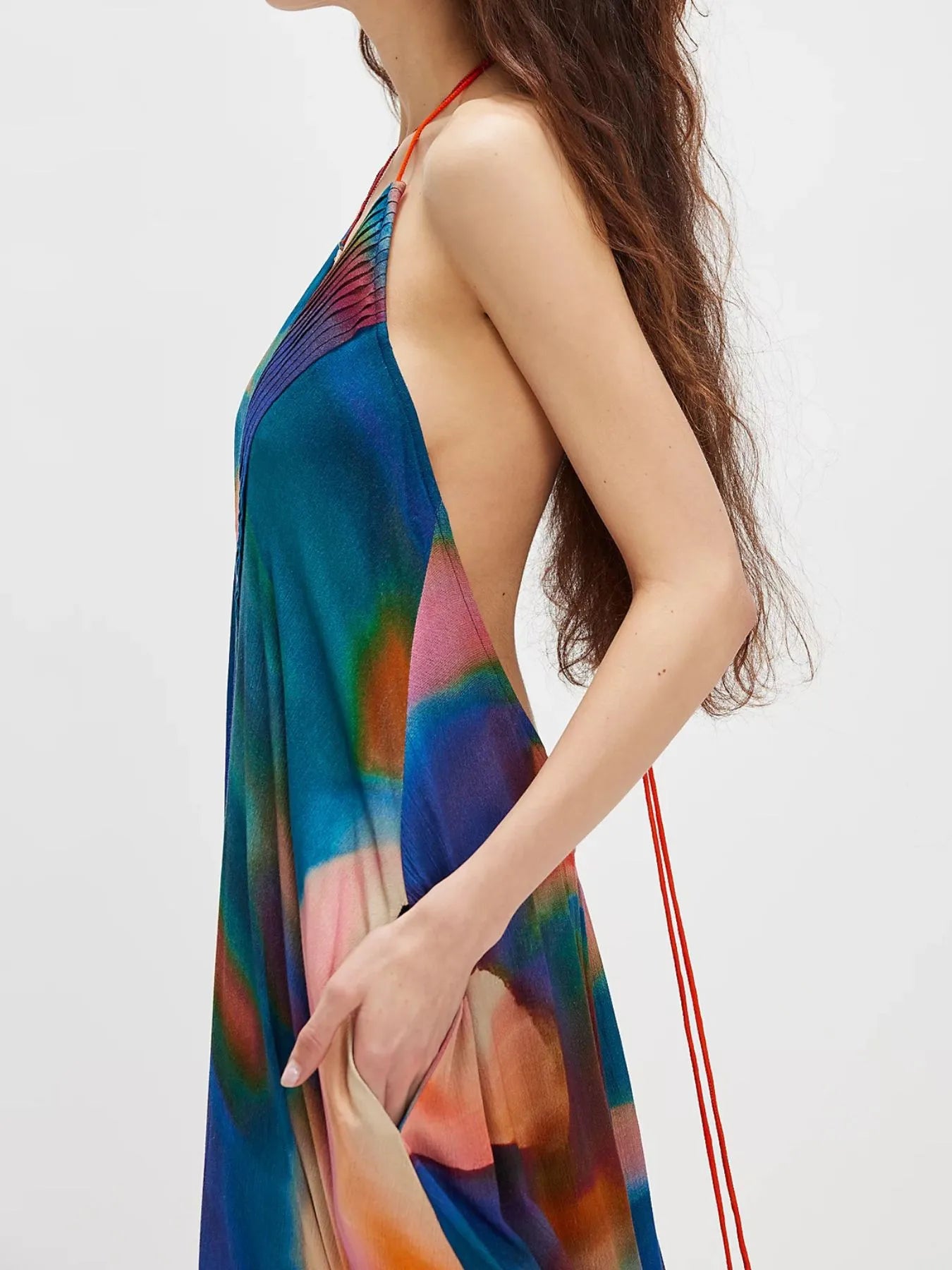 Woman wearing a flowing abstract print halter-neck maxi cami dress with deep neckline.