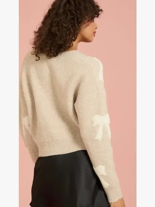 Person wearing a beige sweater with white patterns on a pink background