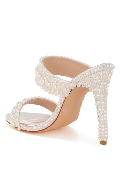 White high-heeled shoe with pearl embellishments on a white background