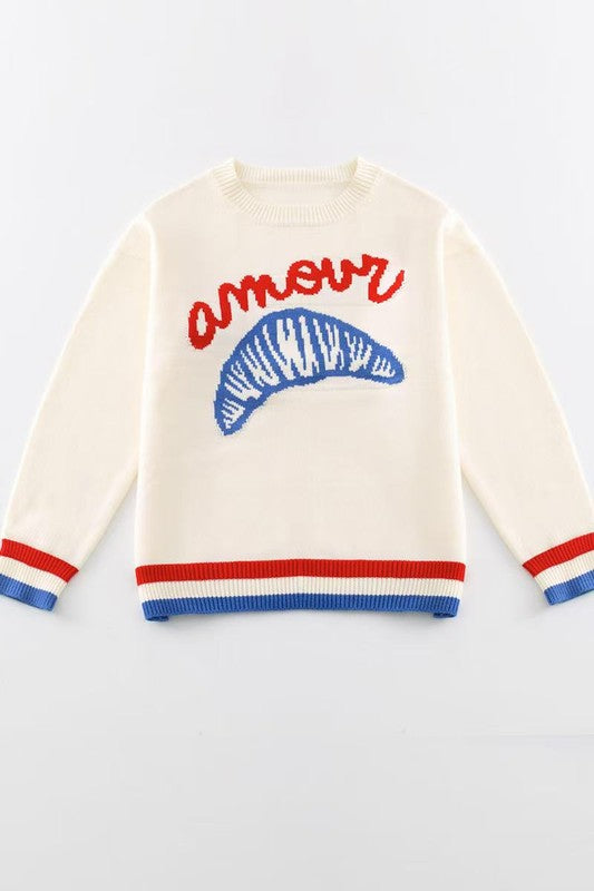 Cream-colored sweater with blue and red accents on a white background