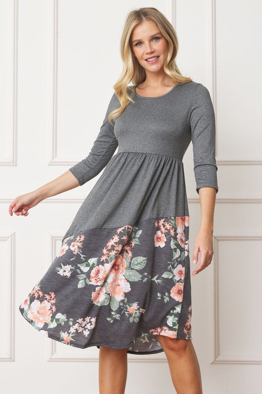 Woman wearing a gray midi dress with a floral pattern on the bottom half, front view.