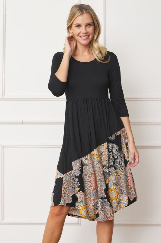 Woman wears a stylish asymmetrical midi dress with a bohemian-inspired pattern, perfect for a unique and trendy look, with hands on hair.