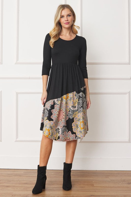 Woman wears a black asymmetrical midi dress with a bohemian-inspired pattern, perfect for a unique and trendy look.