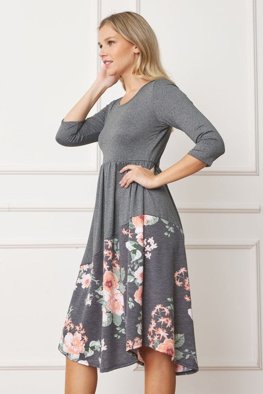 Woman wearing a gray midi dress with a floral pattern on the bottom half, side view.