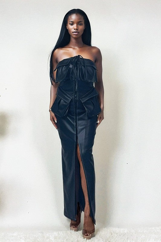 The dress is a sleek, off-shoulder, dark navy gown with a structured bodice, a dramatic draped overlay, and a high slit that reveals one leg.