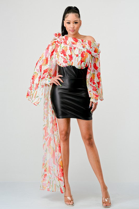 a woman in a black leather mini skirt and a floral print off-the-shoulder top with dramatic sleeves.