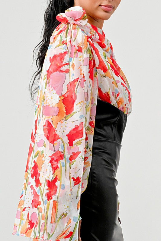 a woman in a black leather mini skirt and a floral print off-the-shoulder top with dramatic sleeves.