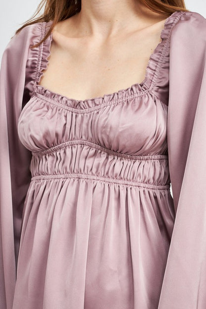 The dress is a puple, long-sleeved mini with a smocked, square-neck bodice and a loose, flowy skirt that falls above the knees.