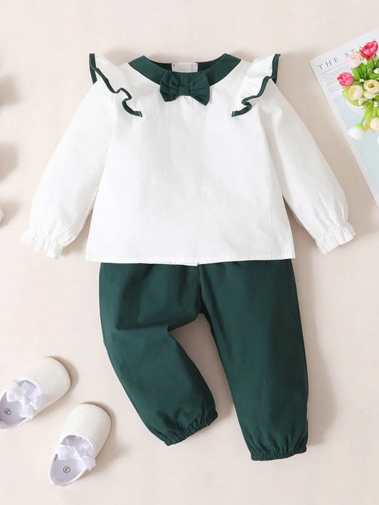 Baby girl two-piece outfit with white ruffled long-sleeve top and green bow accent, and matching green pants with coordinating bow detail

