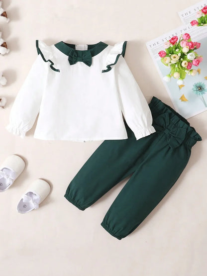 Baby girl two-piece outfit with white ruffled long-sleeve top and green bow accent, and matching green pants with coordinating bow detail

