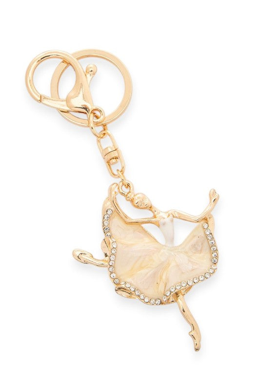 Gold-tone ballerina keychain featuring a dancer in a flowing skirt adorned with sparkling rhinestones. Stylish and elegant accessory for keys or bags.