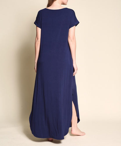 Woman wearing a navy blue maxi dress with short sleeves, barefoot, against a white background.

