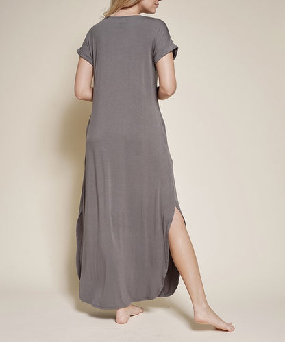 Woman wearing a grey maxi dress with short sleeves, barefoot, against a white background.