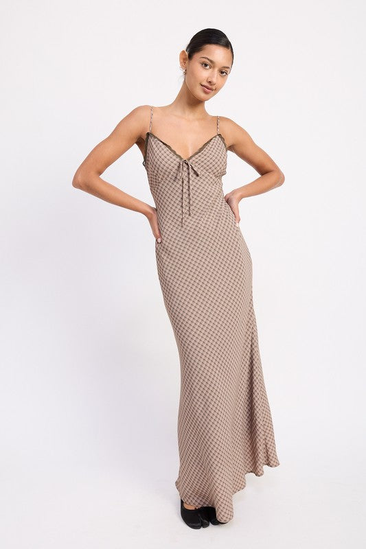 The dress is a form-fitting, floor-length maxi with a soft, neutral taupe color and a delicate, textured fabric