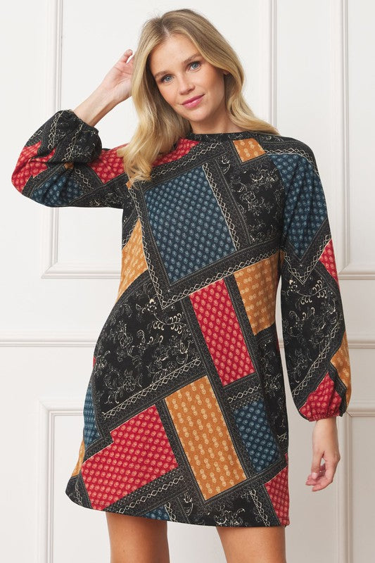 A color-blocked patchwork dress with bold, geometric patterns in red, orange, blue, and black, creating a vibrant, eclectic look.