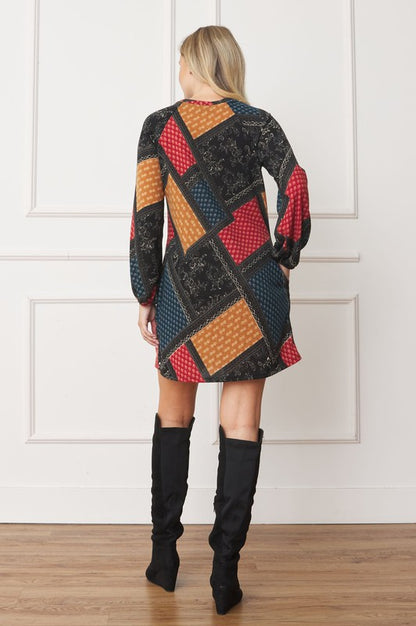 A color-blocked patchwork dress with bold, geometric patterns in red, orange, blue, and black, creating a vibrant, eclectic look.