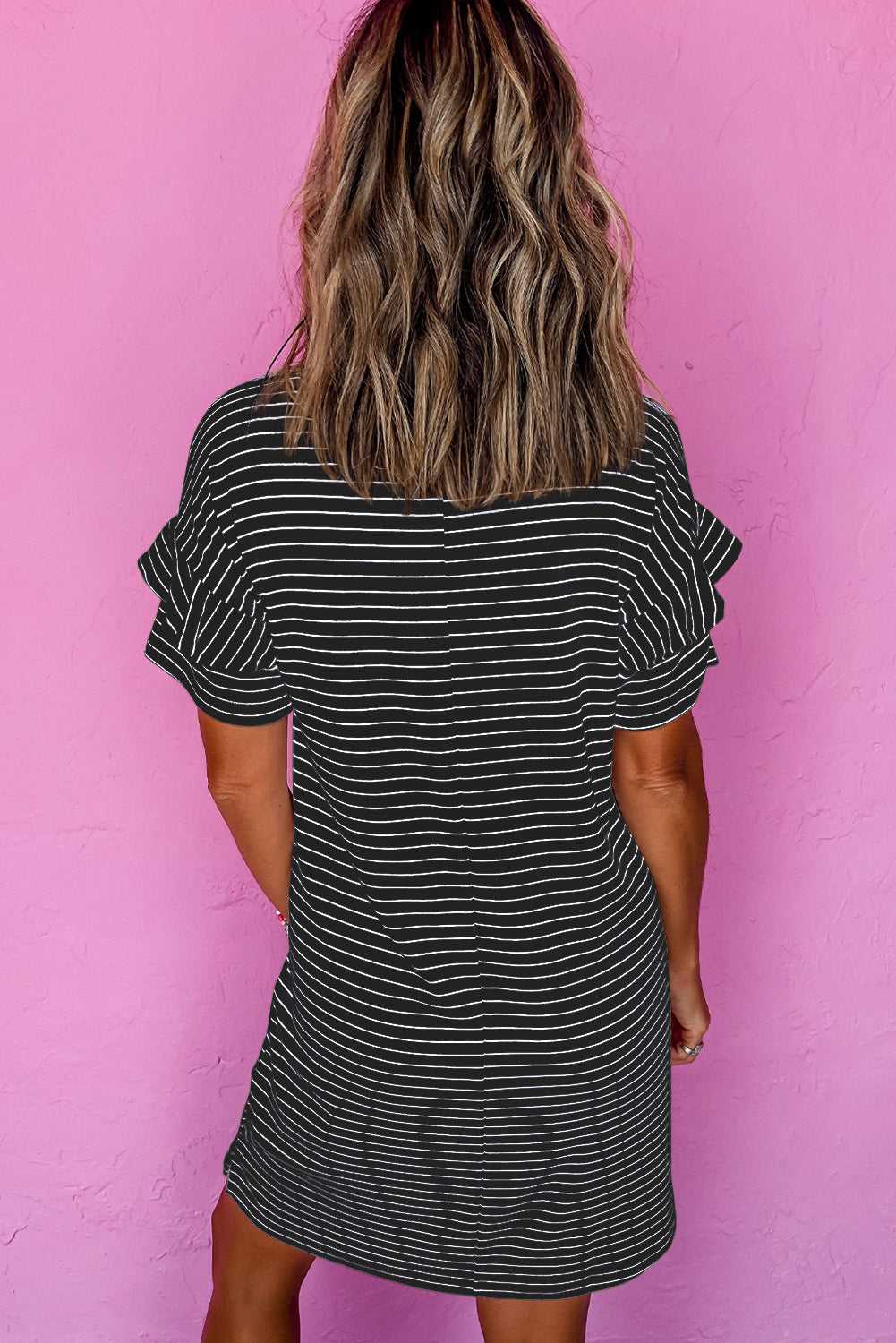 Woman wearing a black striped short-sleeve shift mini dress with ruffled sleeves