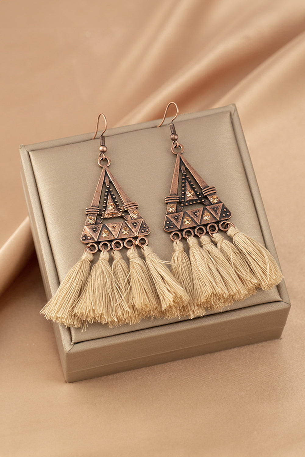 Boho soul, statement style. These earrings are a love letter to laid-back elegance. Featuring a geometric triangle frame in warm-toned metal, finished with cascading brown tassels, they bring movement, texture, and a touch of wanderlust to any outfit.