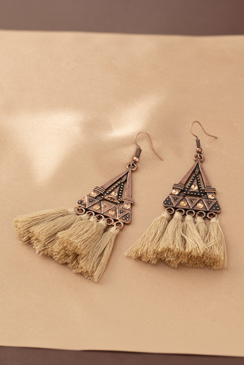 Boho soul, statement style. These earrings are a love letter to laid-back elegance. Featuring a geometric triangle frame in warm-toned metal, finished with cascading brown tassels, they bring movement, texture, and a touch of wanderlust to any outfi