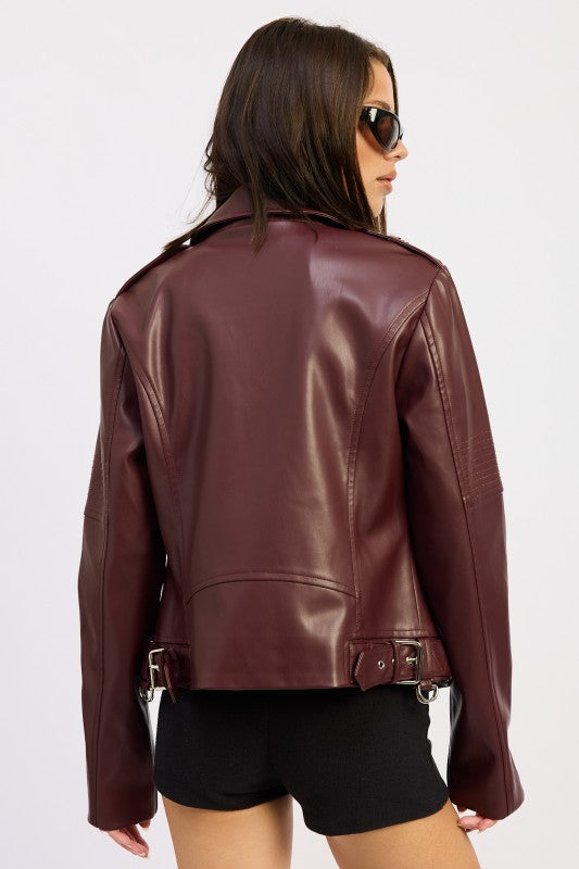 Back view of woman wearing burgundy leather jacket with belt details and black shorts