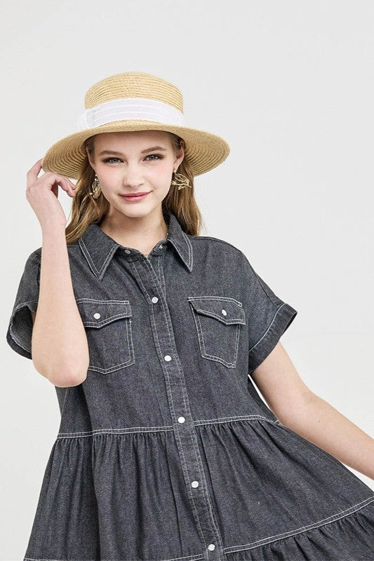 Woman wearing a denim dress and straw hat on a plain background